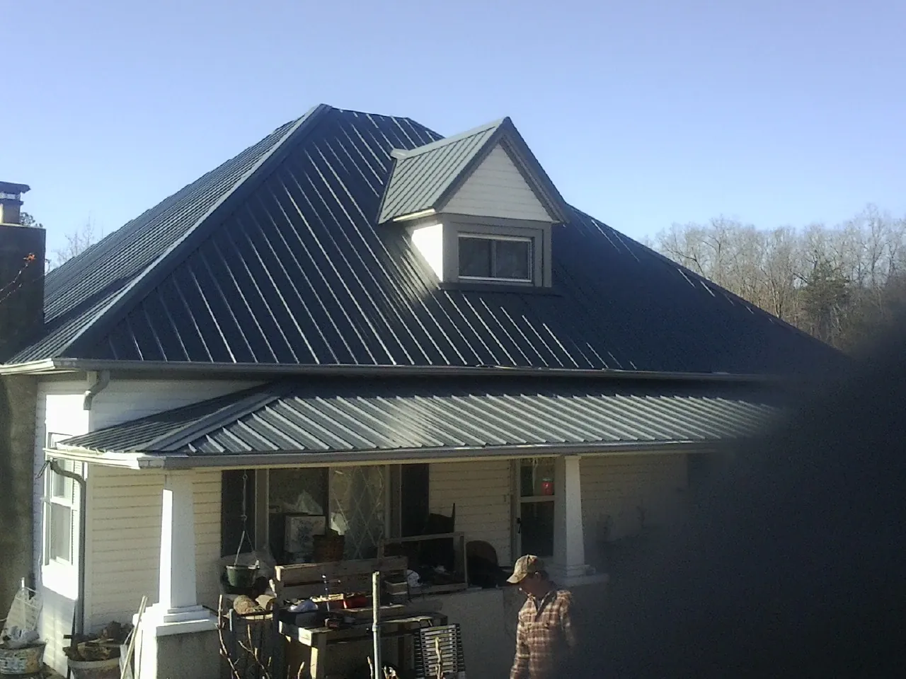 Dark blue standing seam metal roof with a dormer above a front porch in Jamesville