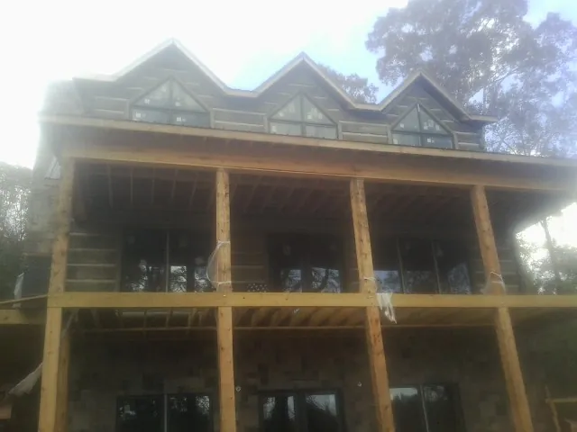 Dormers and porch framing on a large log home under construction — Roof Coating work by our crew in Jamesville